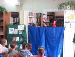 За ширмой петрушка дает представление для детей в библиотеке Ермаково